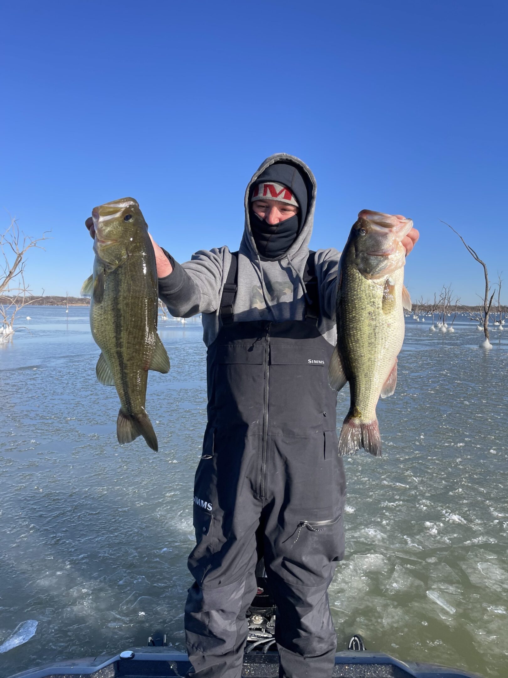Angler holding two large fish on ice